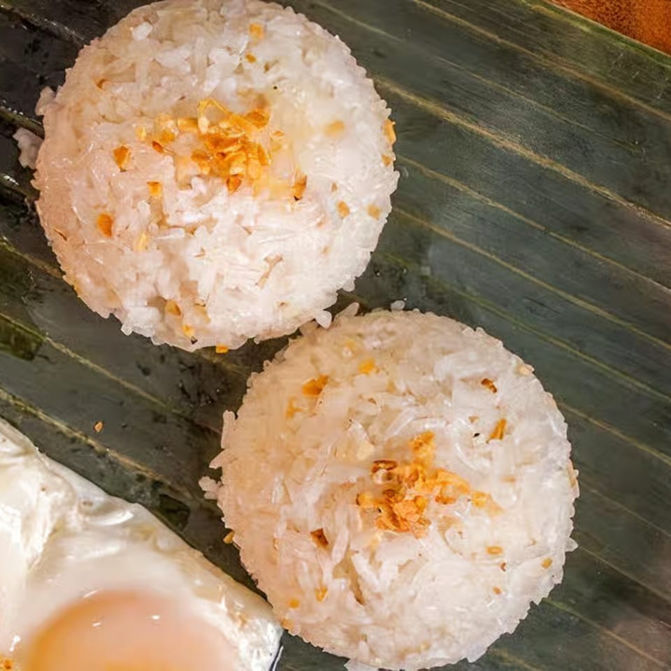 Two mounds of garlic fried rice with a fried egg on a banana leaf at Lutong Bahay.
